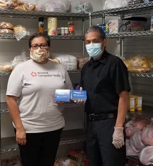 Julia Chavez from Arizona Complete Health presents Anselmo Frias, the Pascua Yaqui’s food pantry assistant, the gift cards to be distributed to families in need.